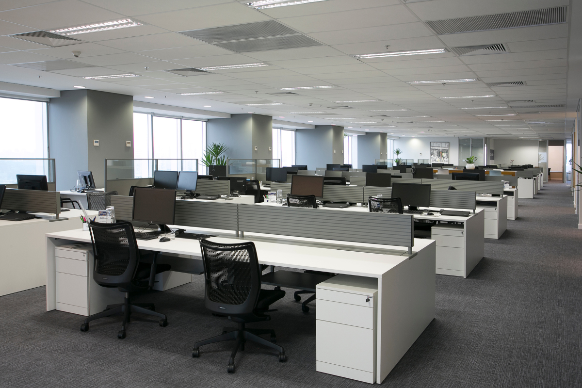 Vista de um escritório corporativo Securit, composto por grandes mesas com painéis divisórios.