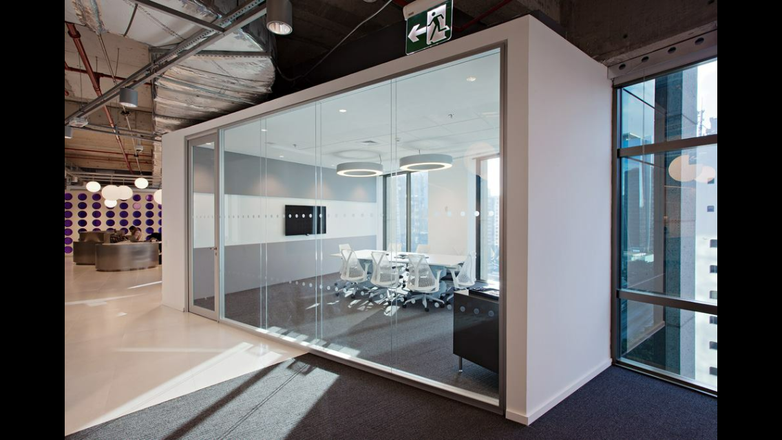 Vista de uma sala de escritório dinâmica estilo cabine acústica, com ambientação composta por mesa de reunião e cadeiras confortáveis.